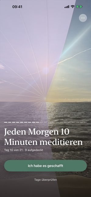 Die App zeigt ein Sonnenuntergangsfoto, teilweise aufgedeckt mit einer violetten Abdeckung, an Tag 10 einer einundzwanzigtägigen Meditationsreise.