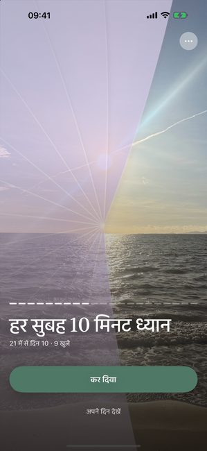 ऐप में सूर्यास्त की एक फ़ोटो, बैंगनी कवर के साथ थोड़ी खुली हुई, इक्कीस दिन की ध्यान यात्रा के दसवें दिन।