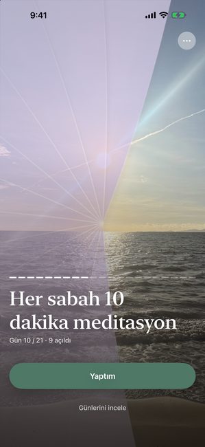 Yirmi bir günlük bir meditasyon yolculuğunun 10. gününde, mor bir örtüyle kısmen açılmış bir gün batımı fotoğrafını gösteren uygulama.